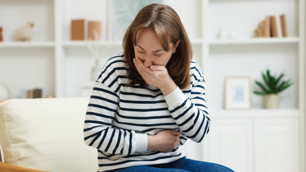 気分が悪そうに口元とお腹に手を当てる女性